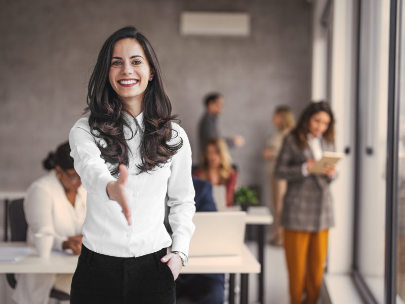 Smiling recruiter reaching out for a handshake, highlighting behavioral profiling in recruitment.